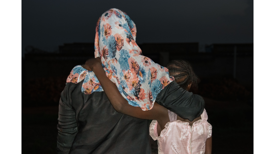 Eine Mutter und Tochter halten sich im Arm. Bild von hinten. Südsudan. Entwicklungszusammenarbeit