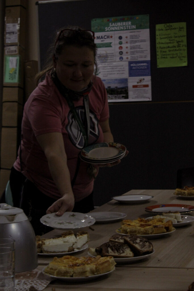 Eine Person deckt den Tisch für gemeinsames Kuchenessen nach dem Müllsammeln für saubere Nachbarschaft in Pirna.